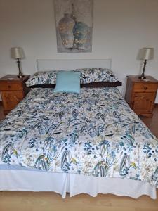 a bed with a blue and white comforter and two night stands at Lurig View B&B Glenariffe in Glenariff