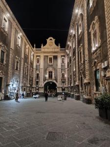 un gran edificio con gente caminando por el patio por la noche en La porta di mezzo, en Catania