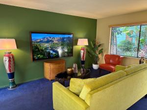 a living room with a yellow couch and a tv at Vista Grande Resort - A Gay Men's Resort in Palm Springs