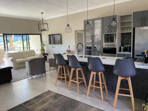 a kitchen with bar stools and a living room at Highland Gate Eagles Breeze in Dullstroom