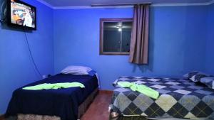 2 letti in una camera con pareti blu di HOSTAL ROZAL SPA HOSPICIO a Alto Hospicio