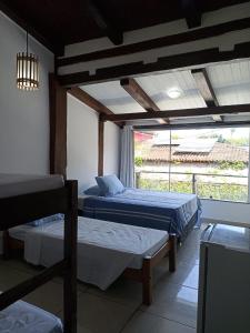 a bedroom with two beds and a large window at Pousada Portal da Mucugê in Porto Seguro