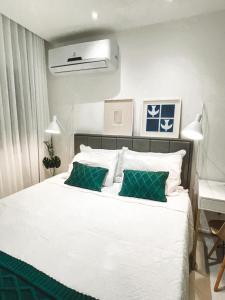 um quarto com uma cama branca e 2 almofadas verdes em Studio Novissimo Perto do Copacabana Palace no Rio de Janeiro