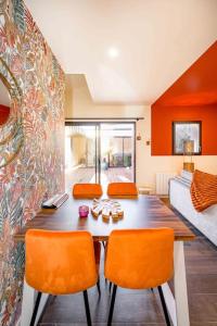 ein Esszimmer mit einem Tisch und orangefarbenen Stühlen in der Unterkunft HOLEN in Langueux
