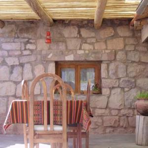 duas cadeiras e uma mesa em frente a um edifício de pedra em La Casa del Indio em Tilcara