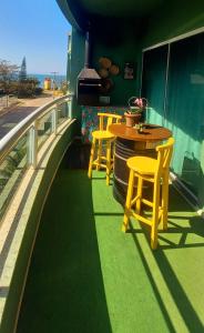 un patio con sillas amarillas y una mesa en el balcón en Residencial Ilha Bela, en Bombinhas