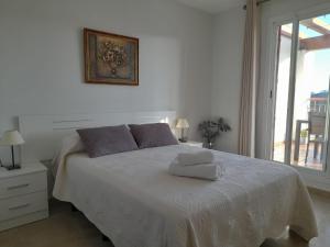 1 dormitorio blanco con 1 cama con 2 toallas en Feel The Vibe Alcaidesa, en San Roque