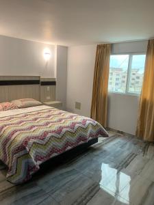 ein Schlafzimmer mit einem Bett und einem großen Fenster in der Unterkunft Hotel Imperial in Santo Domingo de los Colorados