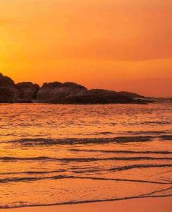 a sunset on the beach with rocks in the water at Salal Suite Ukee in Ucluelet