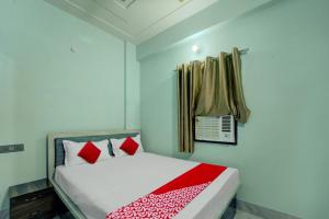 a bedroom with a bed with red pillows and a window at OYO Flagship Hotel R P Royal in Patna
