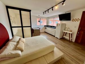 a room with a bed and a kitchen with a refrigerator at Pousada Ilha do Campeche in Florianópolis