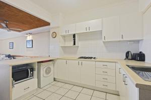 a kitchen with white cabinets and a washer and dryer at Tangalooma Beachfront Villa 23 2 bedroom in Tangalooma +12 photos