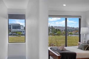 een slaapkamer met een bed en uitzicht op een veld bij Brand New Home In Oran Park in Narellan