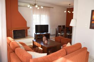 a living room with orange couches and a television at VILLAGE HOUSE in Tríkala