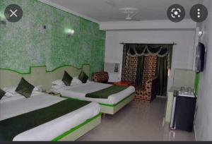 a bedroom with two beds with green walls at Collection O Hotel Gordon House in Katra