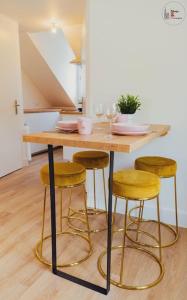 a kitchen with a wooden table with four stools at Le reflet chic - 2 pièces neuf - quartier calme à 5 min de Strasbourg in Schiltigheim