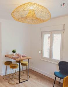 een kamer met een tafel en stoelen en een kroonluchter bij Le reflet chic - 2 pièces neuf - quartier calme à 5 min de Strasbourg in Schiltigheim