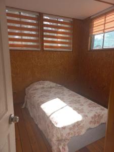 a bedroom with a bed in a room with windows at Cabaña del Quincho Tolpan in Renaico