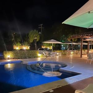 a swimming pool at night with a fountain at Vila das Flores ( vilage) in Itacimirim
