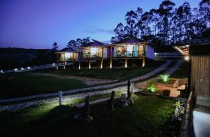 dom w nocy z oświetleniem na trawniku w obiekcie Pousada Paudoro w mieście Conceição do Mato Dentro