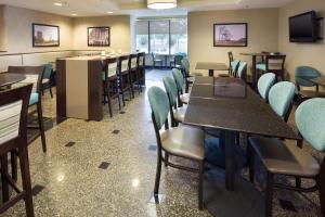 a restaurant with tables and chairs and a television at Drury Inn - Mobile in Mobile