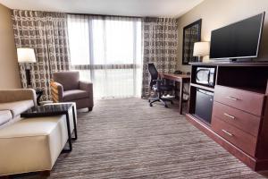 Habitación de hotel con sofá y escritorio con TV. en Drury Inn & Suites Kansas City Airport, en Kansas City