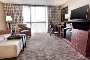 a hotel room with a couch and a desk with a television at Drury Inn & Suites Kansas City Airport in Kansas City