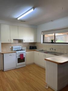een keuken met witte kasten en een witte kookplaat bij 25 Wentworth Street shepparton in Shepparton