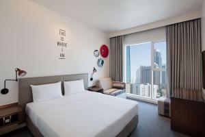a hotel room with a bed and a large window at Rove Trade Centre in Dubai