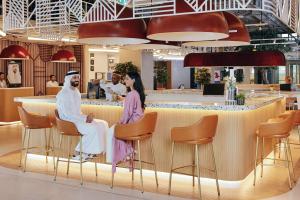 ein Restaurant mit zwei Personen, die an einer Bar sitzen in der Unterkunft Rove Expo City in Dubai
