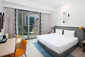 Schlafzimmer mit einem großen weißen Bett, einem Schreibtisch und einem Fenster in der Unterkunft Rove Expo City in Dubai