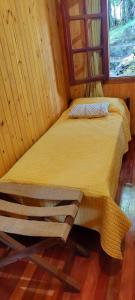 a bed in a wooden room with a window at Cabaña Guabiroba in Dos de Mayo