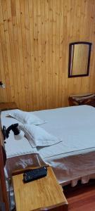 Cabaña Guabiroba في Dos de Mayo: سرير في غرفة مع ريموت كنترول على طاولة