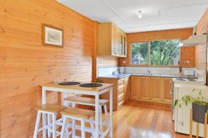 eine Küche mit Holzwänden, einem Tisch und Stühlen in der Unterkunft Mt Elephant Forrest Cabin 
