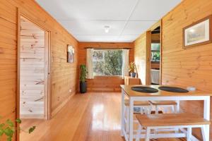 um quarto com paredes de madeira e uma mesa e cadeiras em Mt Elephant Forrest Cabin 