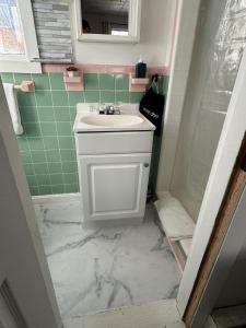 uma casa de banho com um lavatório branco e azulejos verdes em North Beach Motel em Hampton