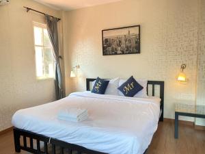 1 dormitorio con 1 cama con sábanas blancas y almohadas azules en jomtien pink villa 4BR en Jomtien Beach