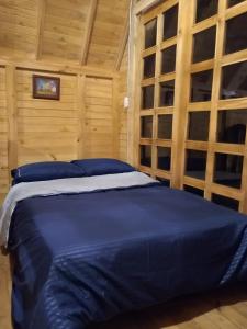 1 dormitorio con 1 cama con sábanas azules y paredes de madera en Sanary, en Guarne
