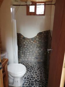a bathroom with a toilet and a rock tile floor at Sanary in Guarne
