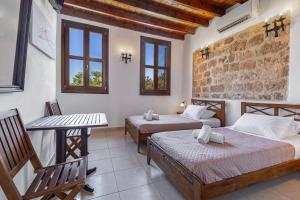 um quarto com duas camas, uma mesa e janelas em Saint Michel Boutique Hotel in Ilha de Rhodes