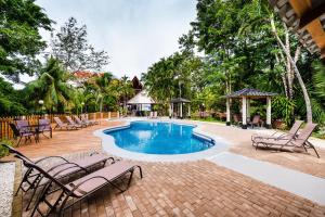 una piscina con sillas y una mesa en El Sueno Tropical Hotel, en Carrillo
