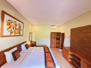 a bedroom with a large bed and a tv at Kawi Homestay Sidemen in Sidemen