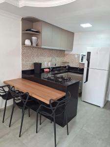 a kitchen with a wooden table and a white refrigerator at Morada do Francês in Praia do Frances