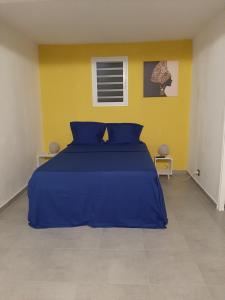 a bedroom with a blue bed and a yellow wall at Zannanna delair in Sainte-Anne