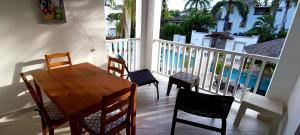 balcón con mesa de madera y sillas y piscina en Tamarindo Dominicus by Mireya, en La Laguna