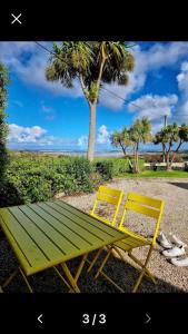 a yellow and green bench sitting next to a tree at The Birdhouse with Hot Tub in Gortahork