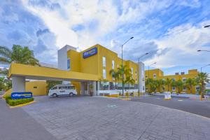 un edificio amarillo con una furgoneta blanca en un estacionamiento en City Express by Marriott Queretaro, en Querétaro