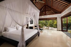 a bedroom with a bed with a mosquito net at OMECURE Kaba Kaba by Nakula in Tabanan