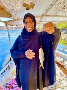 a woman holding a fish on a boat at Heissa Hostel in Aswan