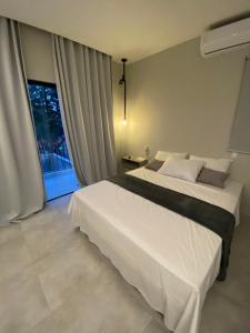Un dormitorio con una gran cama blanca y una ventana en Nossa suíte - Praia da Pipa en Pipa